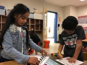 Two young students writing and using manipulatives