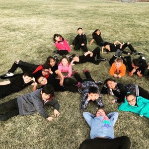 Students sitting on grass outside smiling