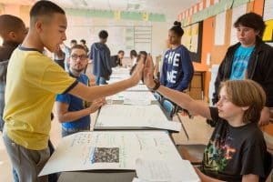 A seventh grader rehearses a science presentation with his classmates.