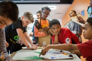 A middle school student explains the inspiration for his art project to classmates.