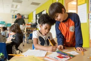 First-grade boy helps girl classmate with assignment