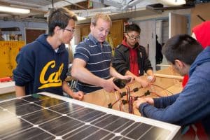 A teacher shows students how to connect the wires to the solar panel to power the boat’s motor. 