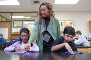 A teacher helps students during a coding lesson at Sutton Middle School