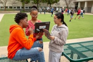 Male Student And Two Female Students With Computers Outside