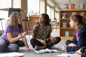 Three middle school students collaborating in the library