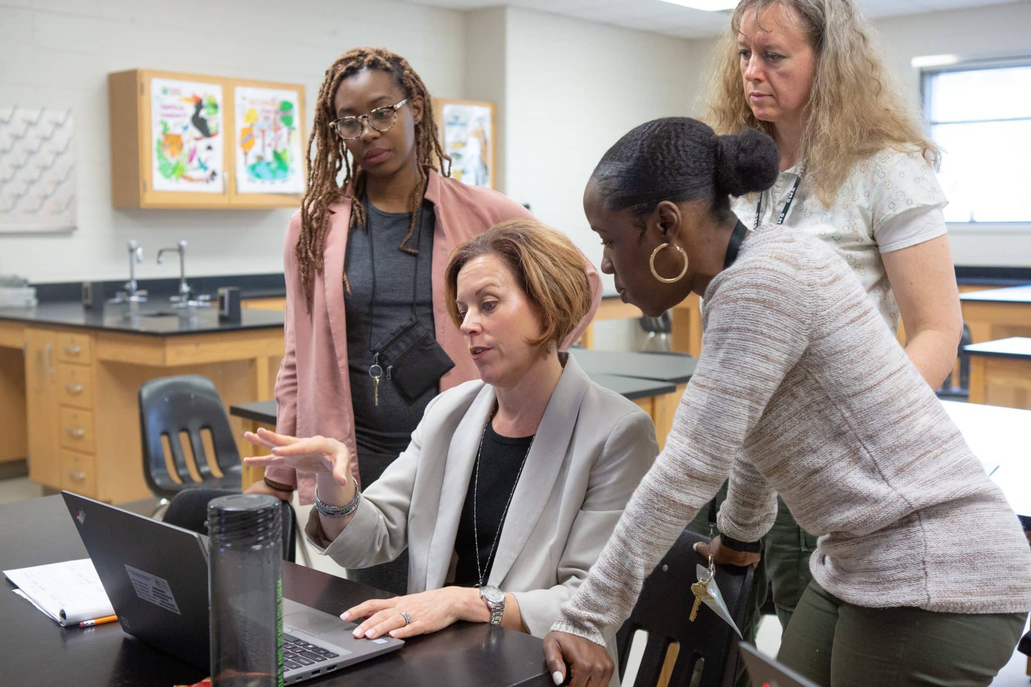 Four teachers working together at a computer