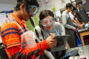 High school students read their lab directions on a computer tablet during AP chemistry class.