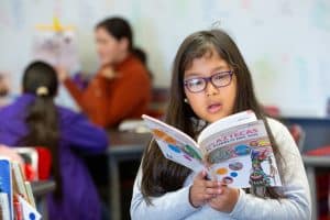 An elementary student reads a book in Spanish to herself.