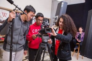 Students in a digital filmmaking class set up the camera in the school studio.