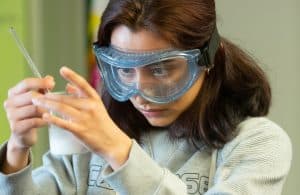 A high school girl mixes chemicals during a chemistry experiment.
