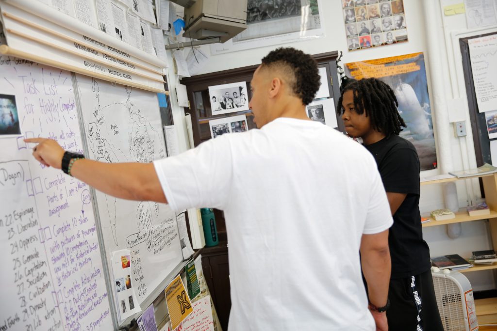 A teacher and student interact at a whiteboard. 