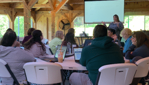 A teacher speaks with a room full of teachers.