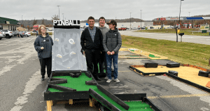 Students standing next to their pinball project. 