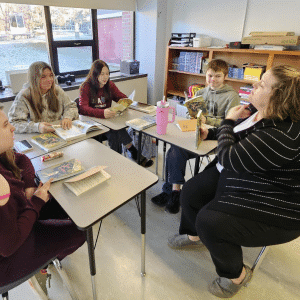 Teacher sitting down with students to discuss an assignment