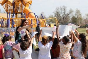 Students holding large paper of their heads outside