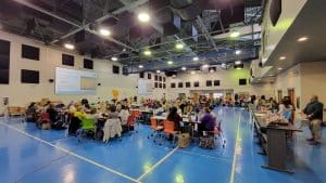 Tables of teachers engaged in conversation in a school gymnasium.