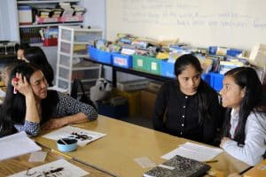 The teacher listening intently to two students.