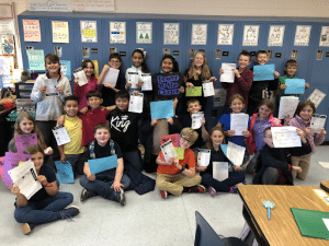A group of students holding up worksheets. 