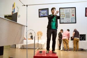 A student from MC2 STEM High School hangs artwork for a school art show.