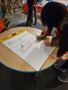 Students writing together on a large notepad for Project Often Reality