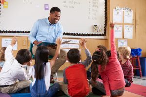 Elementary school kids sitting around teacher in a classroom