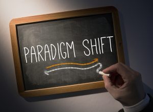 Hand writing the word paradigm shift on black chalkboard