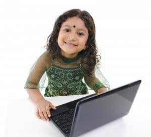 Little Indian girl using a laptop on table, isolated on white background