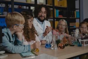 Teacher explaining science experiment to students with beakers in a student-centered learning environment