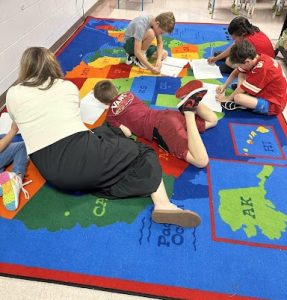 Teacher and students working on a US map rug