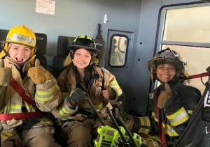 Three high school students dressed in firefighter gear. 